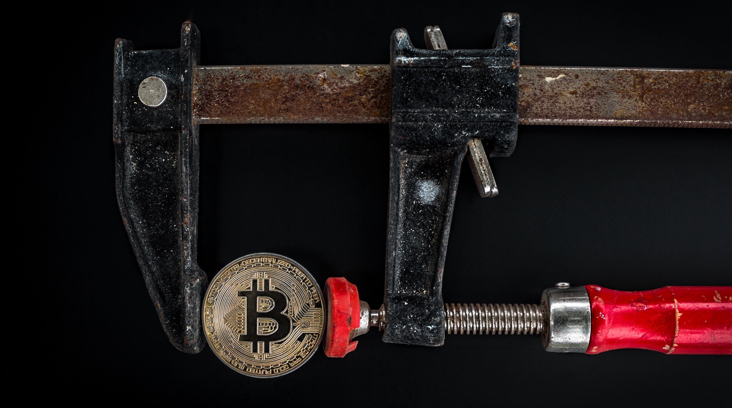 A symbolic bitcoin in a vice.